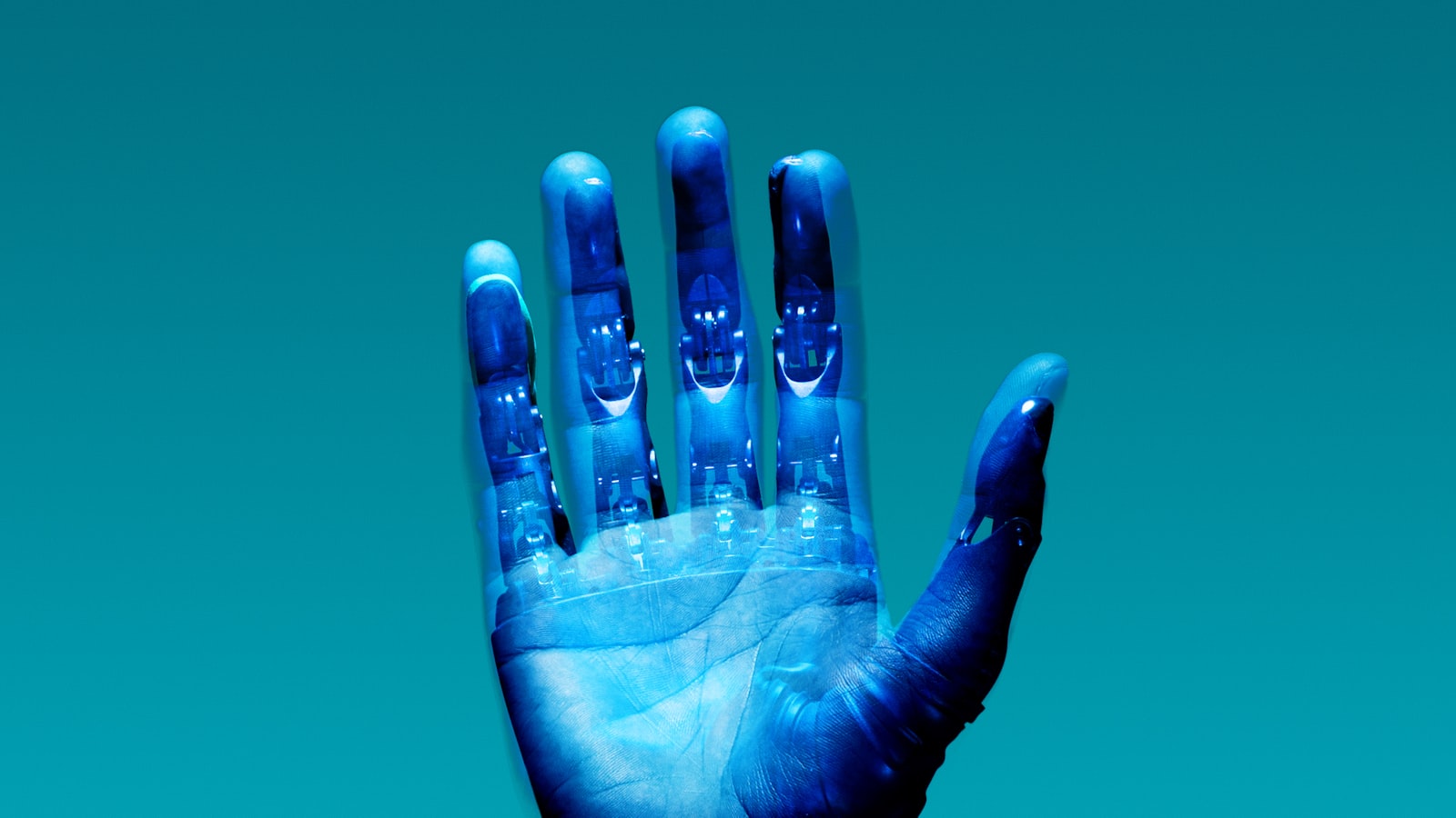 Una mano aperta in luce blu: il palmo è umano, le dita lasciano intravedere una struttura robotica